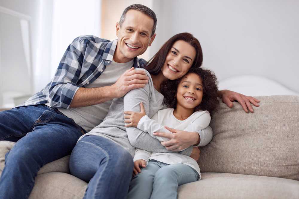 Parents and child embracing on a couch